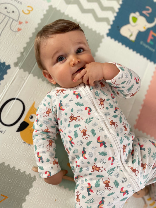 Pyjama modèle jungle porté par un bébé allongé sur un tapis, mettant en évidence la fermeture éclaire.