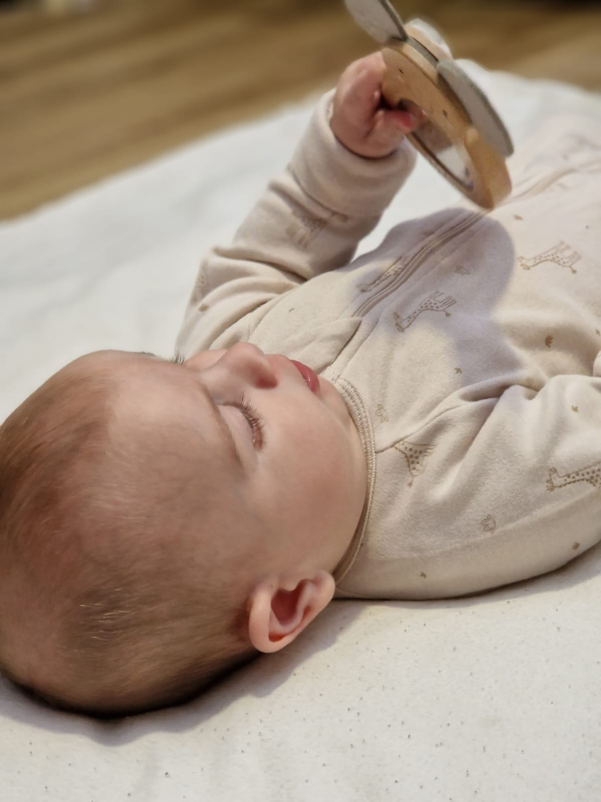 Bébé habillé avec son pyjama zippé et évolutif et qui joue avec son hochet