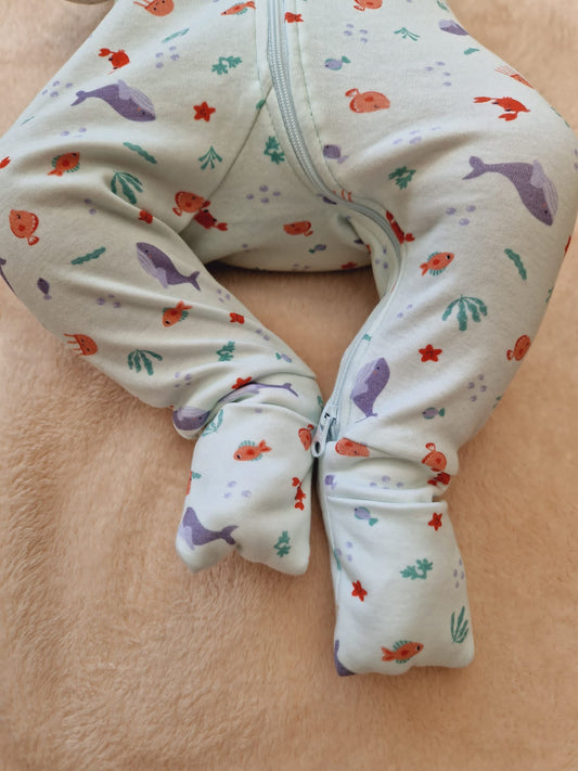Focus sur la partie bas du corps du bébé présentant les pieds au chaud avec les chaussettes retroussables fermées.