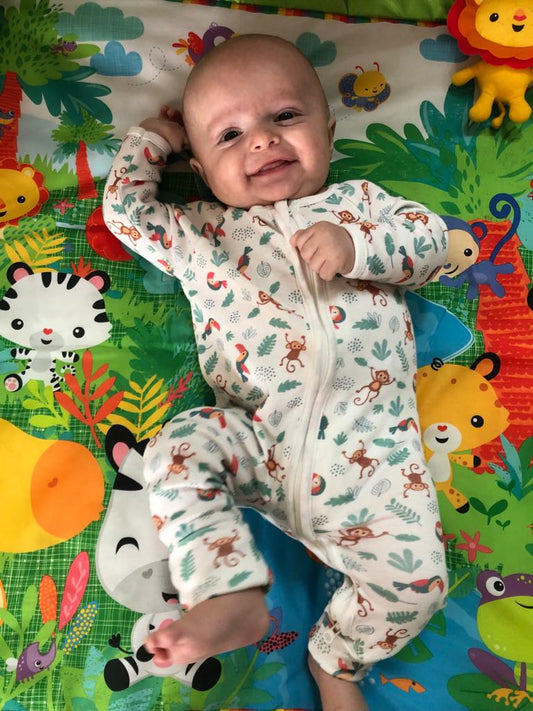 Bébé vêtu du pyjama de la collection jungle avec ses petits pieds à l'air.